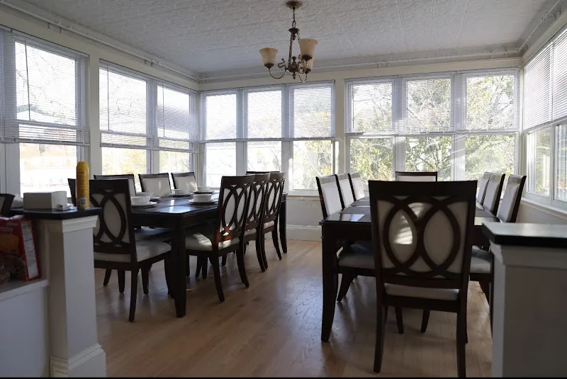Bright dining area with large windows at Patty's Sanctuary Sober Living, a sober living home in Boston.