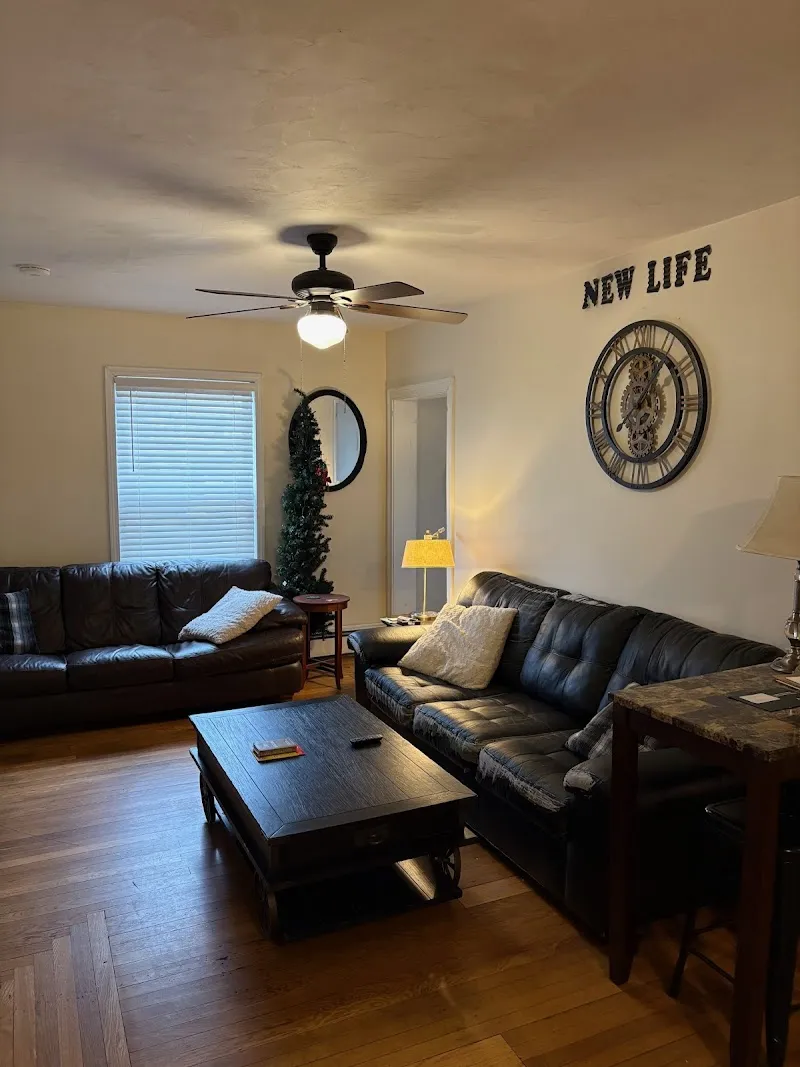 Cozy living room with leather sofas at New Life Sober Living, a sober living home in Boston.